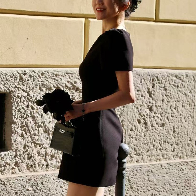 Women's black short puff sleeve mini dress with a stylish boat neckline design and pocket details, suitable for elegant occasion