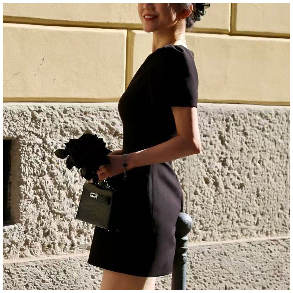 Women's black short puff sleeve mini dress with a stylish boat neckline design and pocket details, suitable for elegant occasion